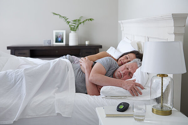 Paar schläft im Bett, neben ihnen die Inspire Fernbedienung