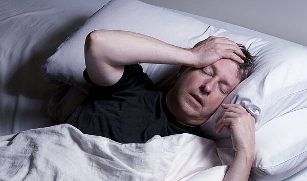 Schlafloser Mann im Bett. Schlafstörungen schaden der Gesundheit.