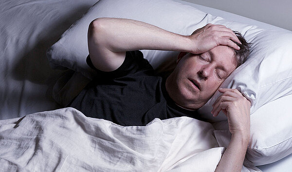 Schlafloser Mann im Bett. Schlafstörungen schaden der Gesundheit.