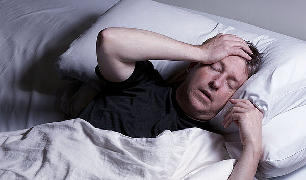 Schlafloser Mann im Bett. Schlafstörungen schaden der Gesundheit.