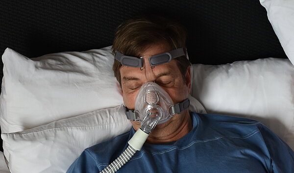 Schlafender Mann mit CPAP Maske