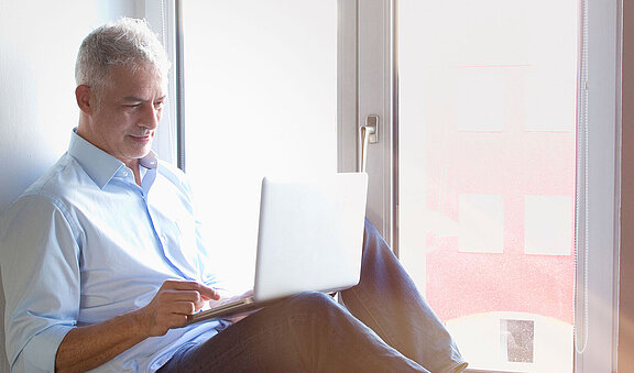 Mann am Fenster liest am Tablet über die Inspire-Therapie  