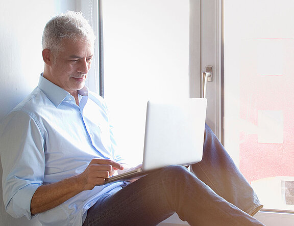 Mann am Fenster liest am Tablet über die Inspire-Therapie  