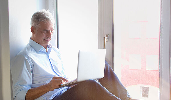 Mann am Fenster liest am Tablet über die Inspire-Therapie