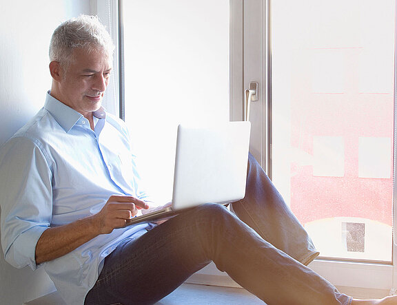 Mann am Fenster liest am Tablet über die Inspire-Therapie  