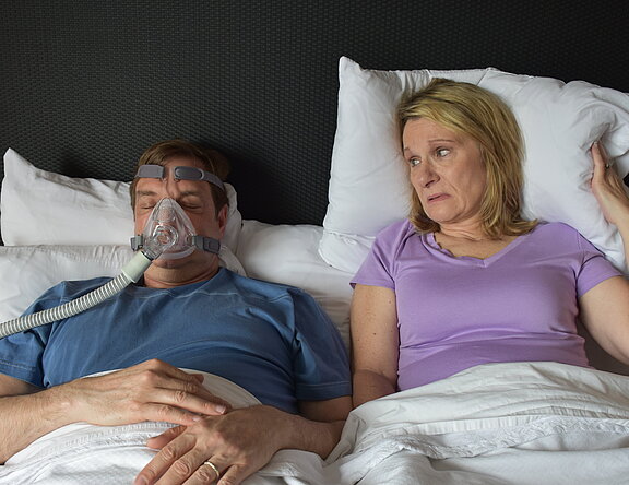 Im Bett: Er trägt eine CPAP-Maske, sie wird dadurch beim Schlafen gestört.  