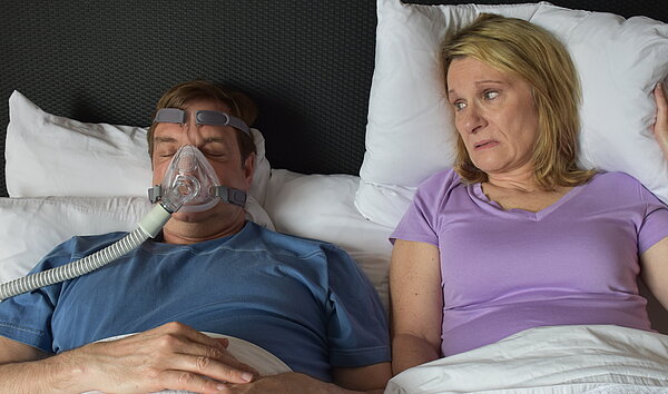 Im Bett: Er trägt eine CPAP-Maske, sie wird dadurch beim Schlafen gestört.