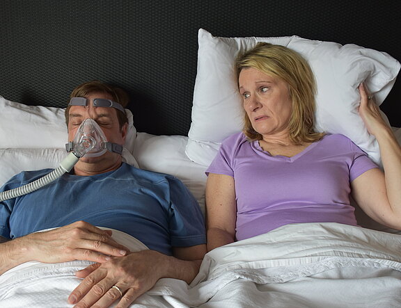 Im Bett: Er trägt eine CPAP-Maske, sie wird dadurch beim Schlafen gestört.  