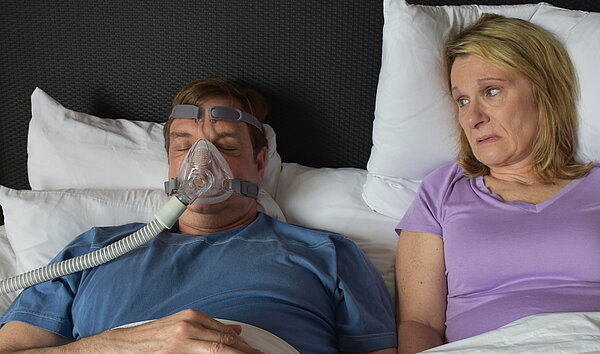 Im Bett: Er trägt eine CPAP-Maske, sie wird dadurch beim Schlafen gestört.