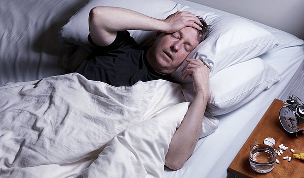 Mann mit Schlafapnoe liegt im Bett und kann nicht schlafen