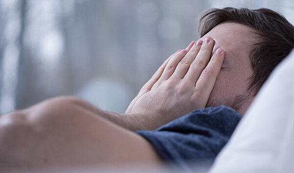 Schlafloser Mann im Bett. Schlafstörungen schaden der Gesundheit.