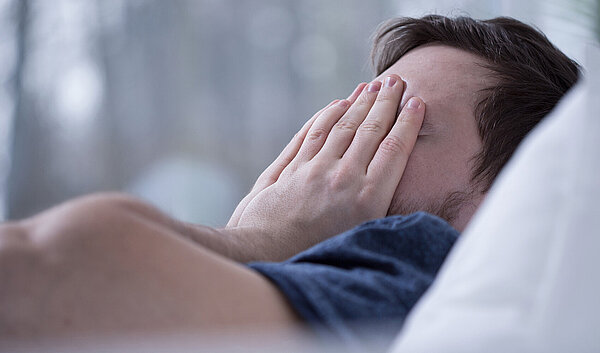 Schlafloser Mann im Bett. Schlafstörungen schaden der Gesundheit.