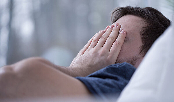 Schlafloser Mann im Bett. Schlafstörungen schaden der Gesundheit.