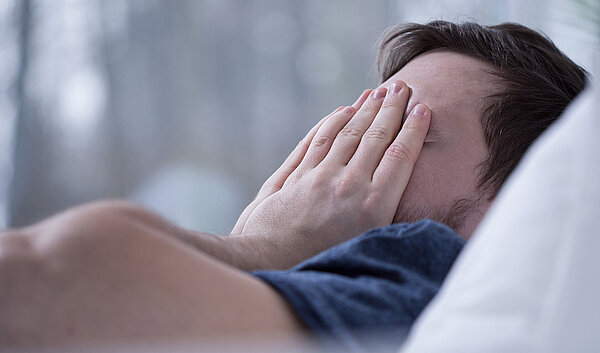 Schlafloser Mann im Bett. Schlafstörungen schaden der Gesundheit.