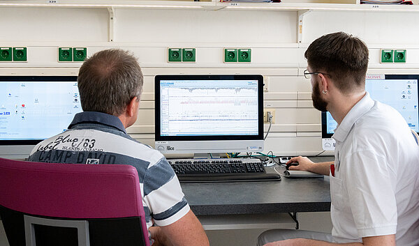 Patient und Arzt sitzen vor einem PC. Auswertung im Schlaflabor