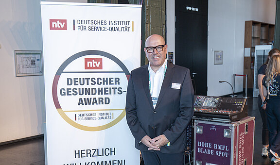 Andreas Henke, Senior Vice President und  Managing Director Europe von Inspire Medical Systems Europe GmbH, vor dem Schild „Deitscher Gesundheits-Award"