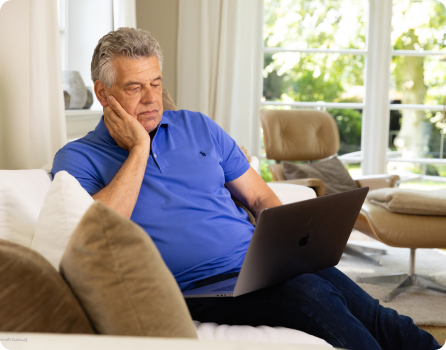 Fotografie von Inspire Nutzer Jürgen Hingsen, der mit seinem Laptop auf dem Sofa sitzt und die Inspire Therapie mit dem Zungenschrittmacher recherchiert.